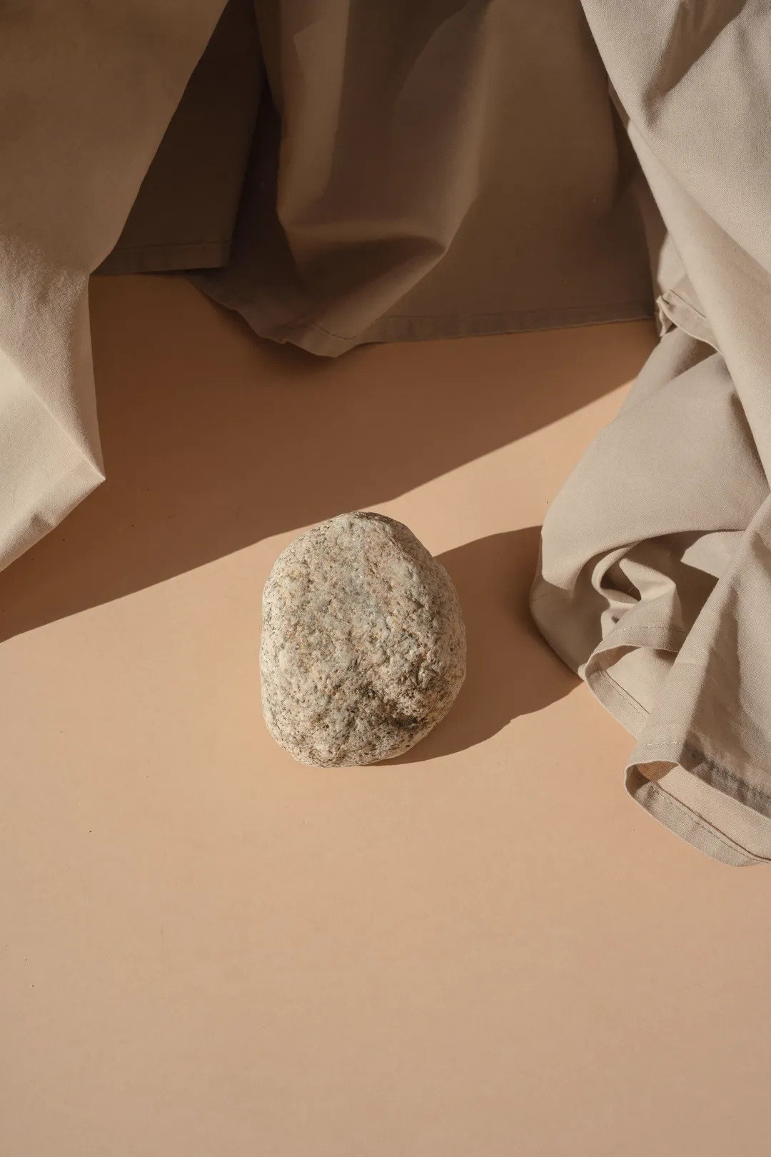 Warm still life, stone and folded linen on a side table